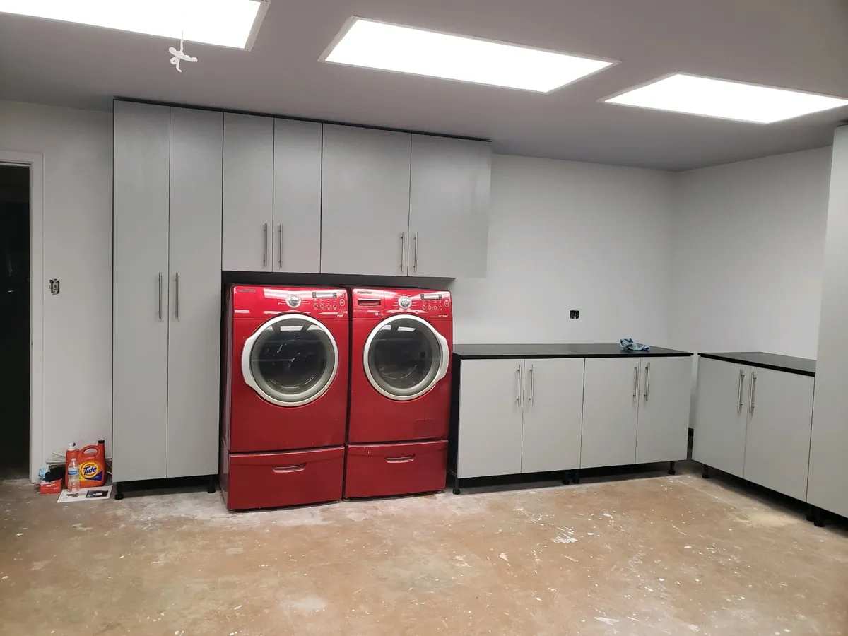 A custom laundry room with folding counter, storage cabinets and pull-out hampers