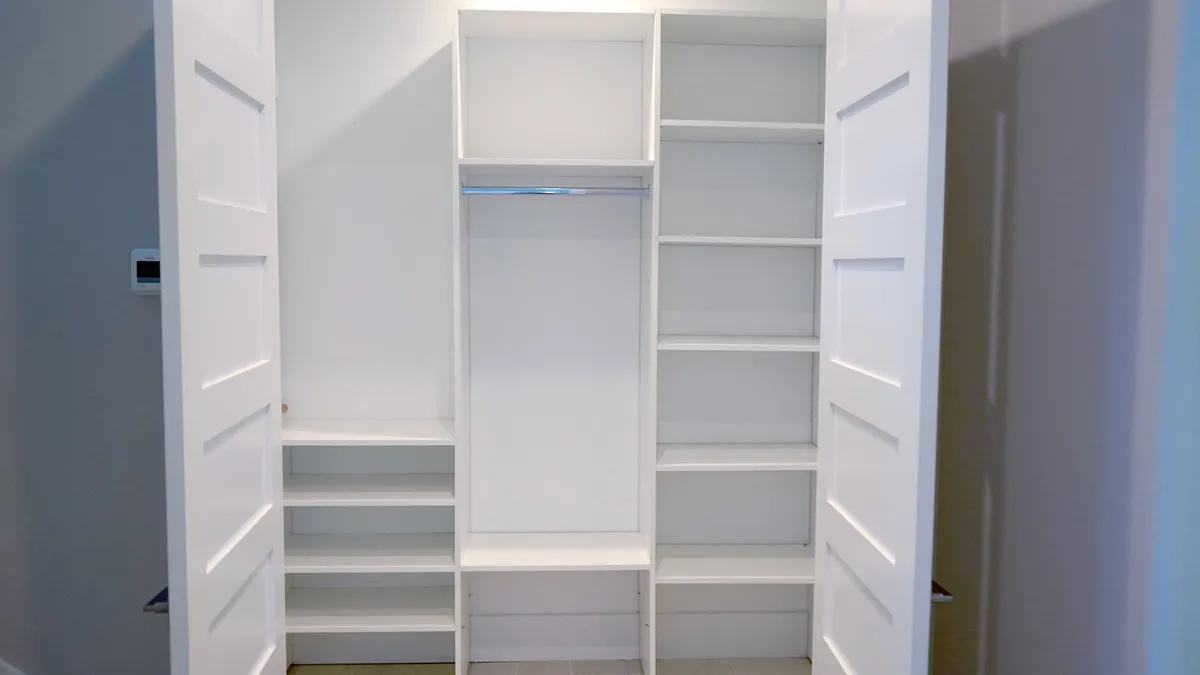 A custom reach-in closet with double-hang sections and built-in drawers
