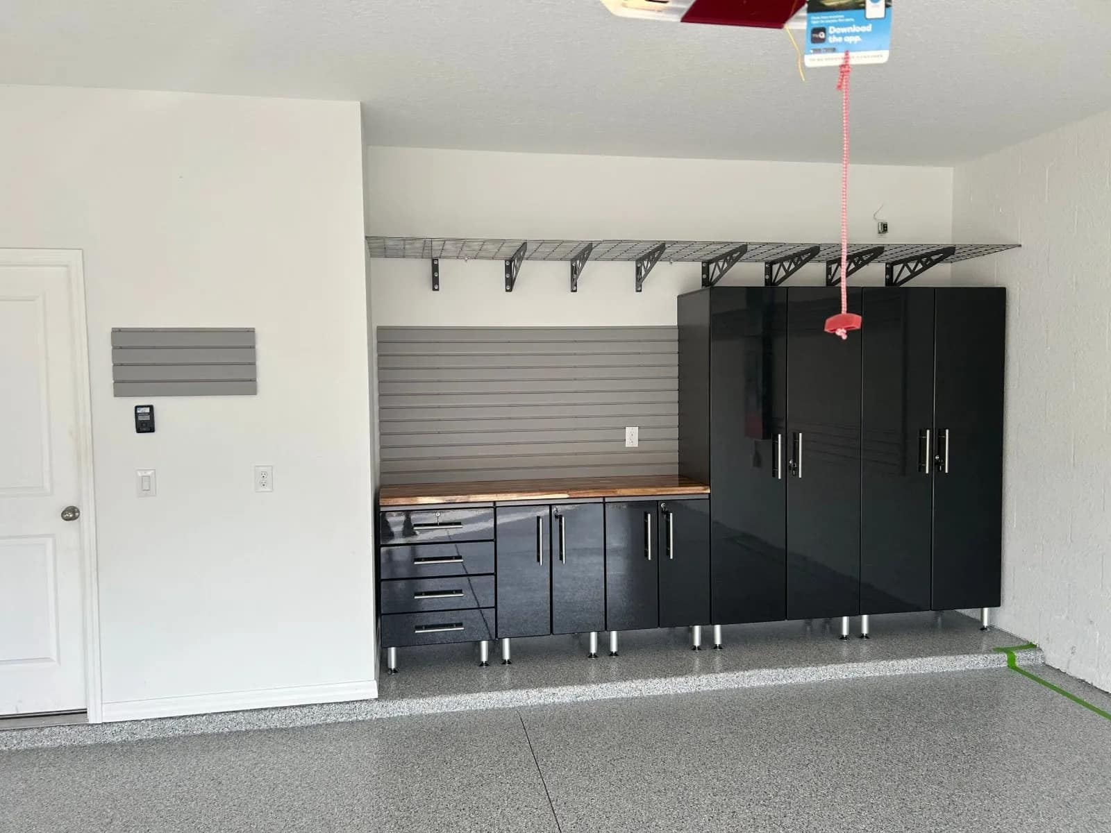 A finished garage with custom cabinets, slatwall and overhead storage racks