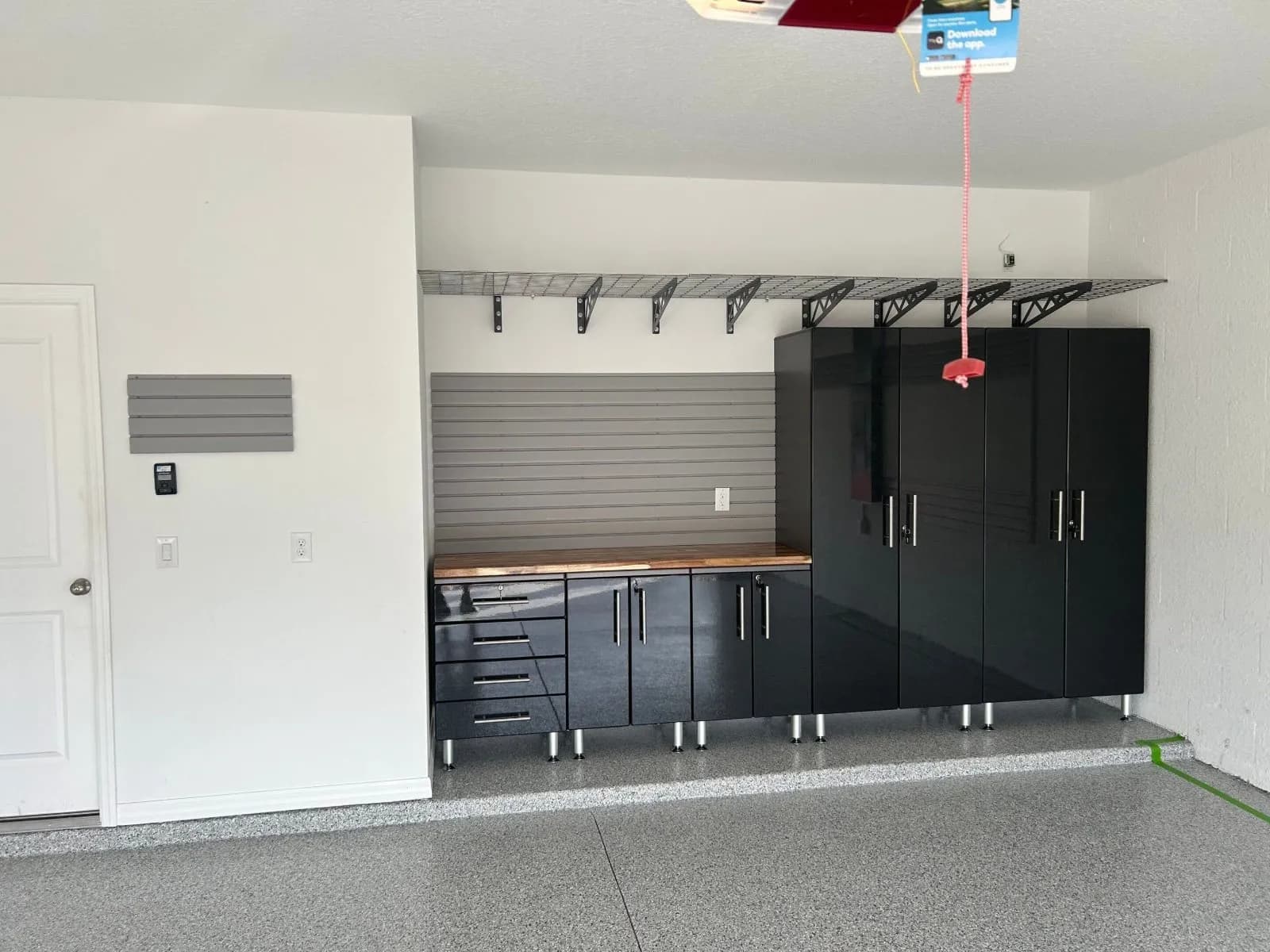 A finished garage with custom cabinets, slatwall and overhead storage racks